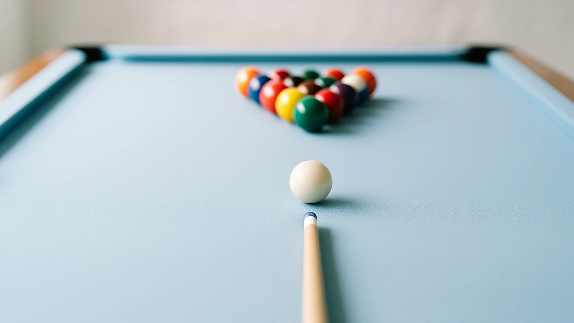 A pool cue lined up behind the cue ball, aimed at a racked set of balls on blue cloth