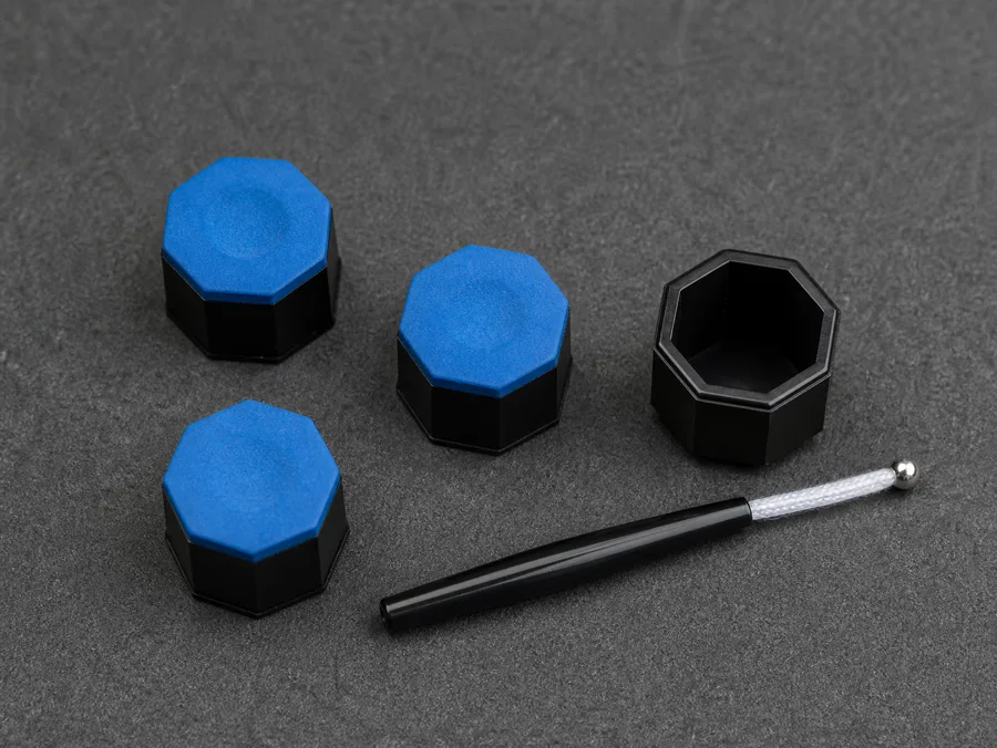 Three blue octagonal chalk pieces and an open black octagon chalk holder