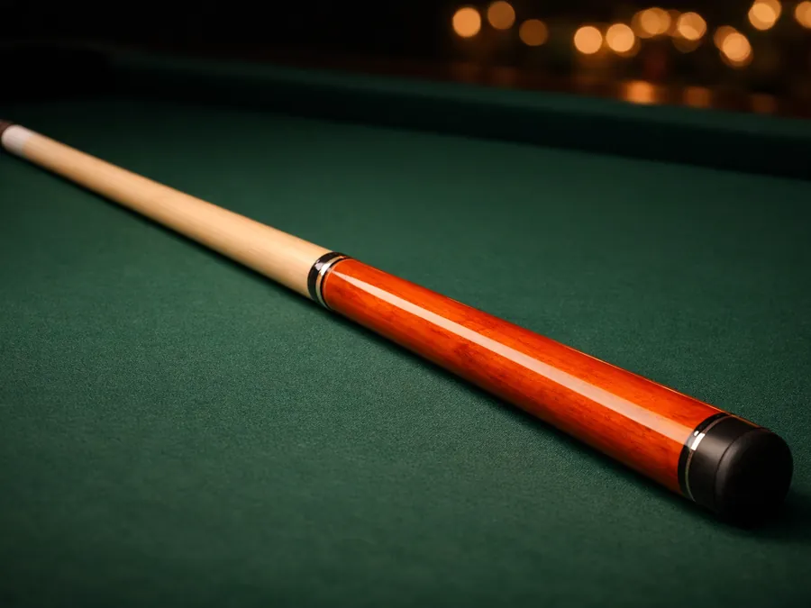 A maple pool cue with an orange stained butt lying on green cloth
